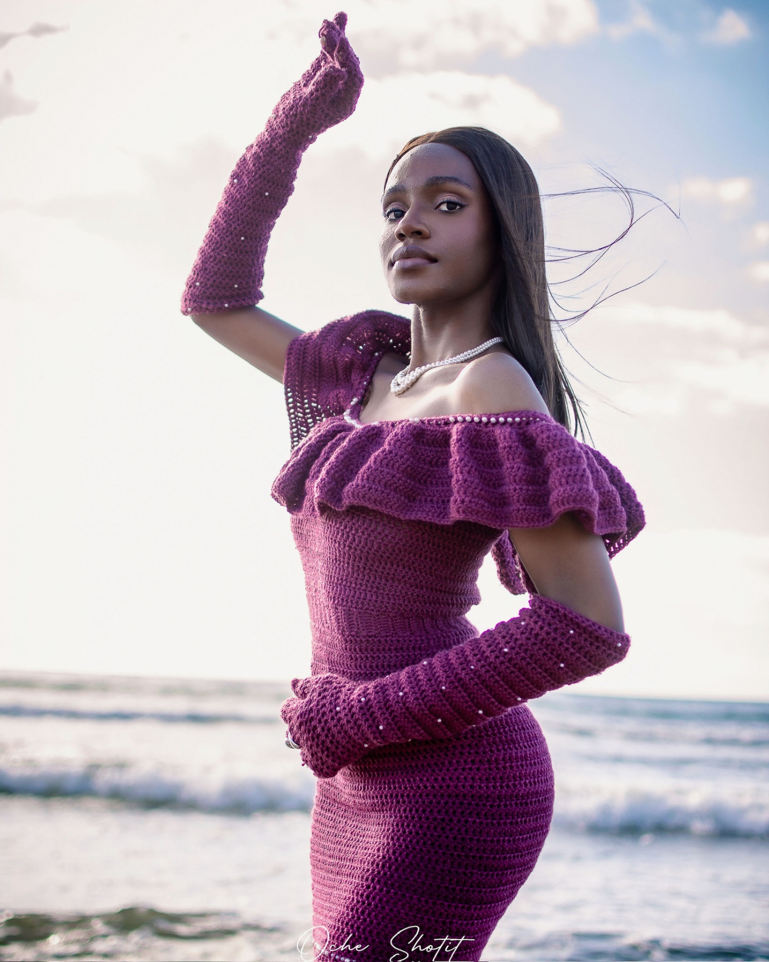 Dibi in a plum crochet dress with pearl details by the sea